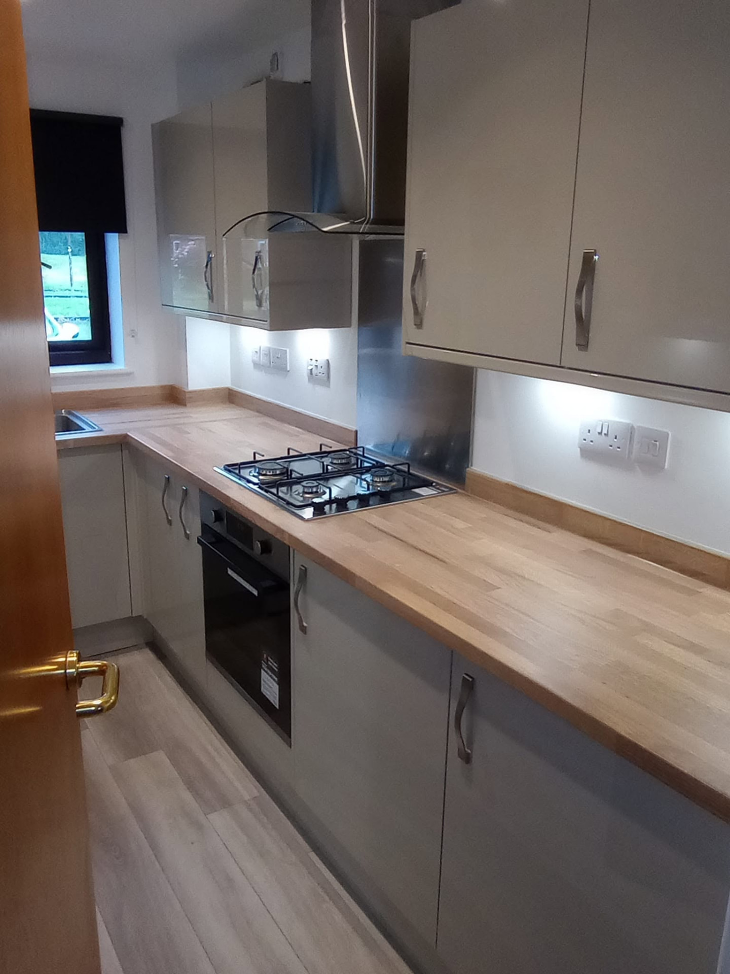 Finished grey kitchen with timber worktops, extractor and fitted appliances